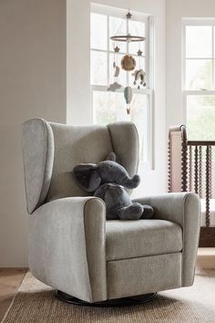 an elephant stuffed animal sitting on top of a chair in front of a baby crib