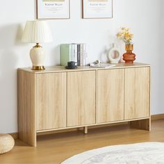 a wooden cabinet with two pictures on the wall above it and a lamp next to it