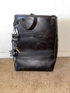 100% handmade leather tote bag black in color with gunmetal colored rivets. Comes with a matching colored keychain. Leather Tote Bag With Metal Hardware, Everyday Use Satchel Tote With Metal Hardware, Everyday Satchel Tote With Metal Hardware, Bucket Satchel With Metal Hardware For Everyday Use, Everyday Bucket Satchel With Metal Hardware, Tote Bag With Metal Hardware For Everyday Use, Tote Satchel With Metal Hardware, Leather Bucket Bag With Gunmetal Hardware For Everyday, Everyday Leather Bucket Bag With Gunmetal Hardware