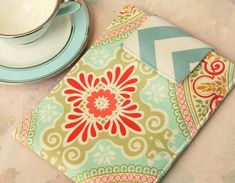 a cup and saucer sitting on top of a table next to a napkin with a flower design