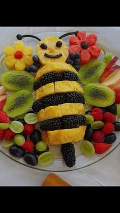 a glass plate topped with sliced fruit and a bee decoration on top of the plate