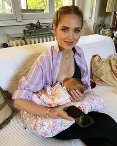 a woman sitting on a couch holding a baby