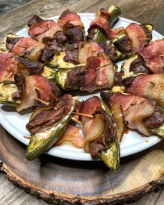 bacon wrapped jalapenos on a white plate sitting on top of a wooden table