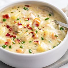 a white bowl filled with soup on top of a table next to a fork and napkin