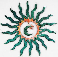 a green and orange metal sun ornament on a white background with an arrow in the center