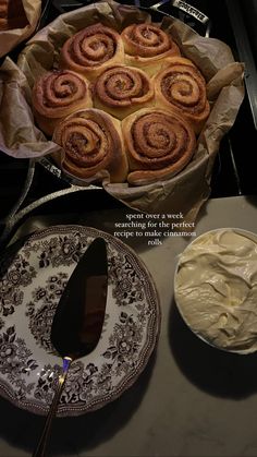 there is a plate with some cinnamon rolls on it next to a bowl of cream cheese