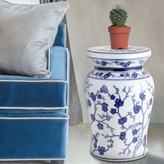 a blue and white vase sitting on top of a table next to a couch with a potted plant