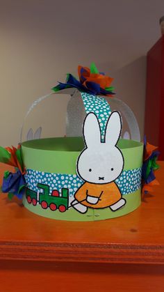 a paper hat with an image of a rabbit on the front, and a train in the back