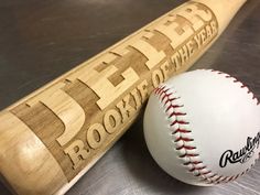 a baseball bat and ball sitting on top of a wooden table next to each other