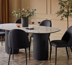 a dining table with four chairs around it and two wine glasses sitting on the table