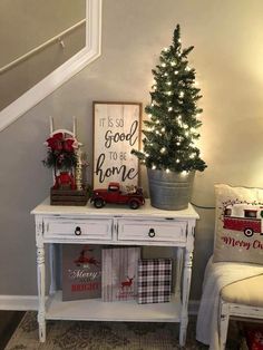 a small christmas tree sitting on top of a white table next to a couch and chair