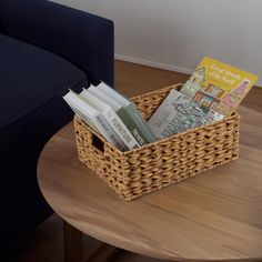 a wicker basket filled with books sitting on top of a table next to a blue couch