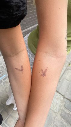 two people with matching tattoos on their arms, one is holding the other's hand