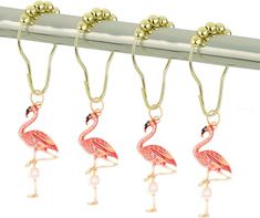 four flamingos hanging from a metal bar with gold balls on it's hooks