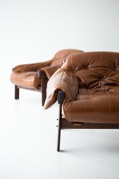 two brown leather chairs sitting next to each other