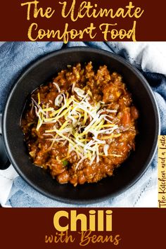 the ultimate comfort food chili with beans and cheese in a black bowl on top of a blue towel