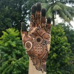 a hand with henna on it and trees in the background