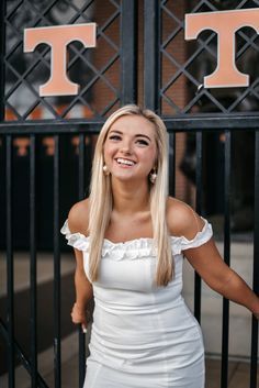 a beautiful young woman standing in front of a gate