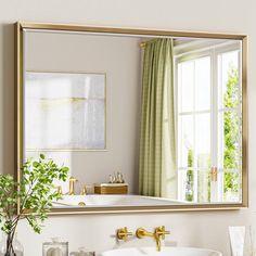 a bathroom sink sitting under a large mirror next to a white counter top with gold faucet