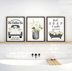 three framed art prints on the wall above a bathtub with flowers in a vase