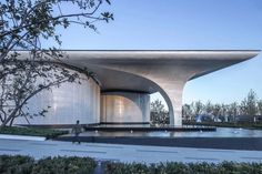 an architecturally designed building with a fountain in the foreground and trees around it