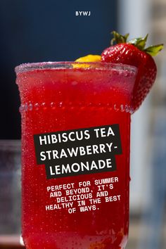 a red drink in a glass with a strawberry on the top and label that says hibiscus tea strawberry lemonade