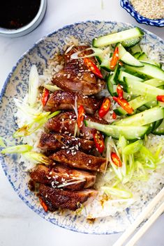 a blue and white plate topped with meat and veggies next to chopsticks