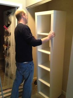 a man standing in front of a book shelf with his hand on the door handle