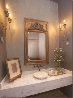 a bathroom with a sink, mirror and framed pictures on the counter top in front of it