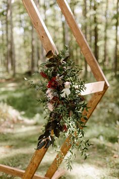 a wedding arch decorated with flowers and greenery for an outdoor ceremony in the woods