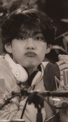 black and white photograph of a young boy with headphones in front of microphones