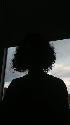 the silhouette of a person in front of a window