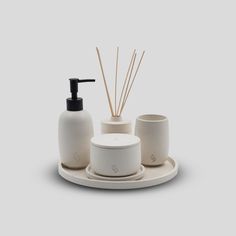 a soap dispenser and two cups on a tray with reeds in it