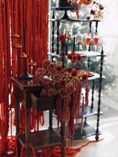 a vase with flowers on a table in front of a christmas tree and orange curtains