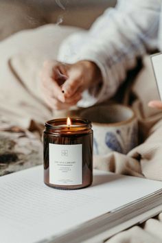 a candle sitting on top of a bed next to a book