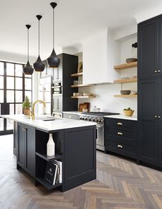 a large kitchen with black cabinets and white counter tops, an island in the middle