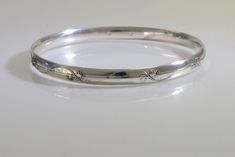 "This beautiful sterling silver bangle looks great alone, or stacked with our other bangles. It is embossed with a unique vine and leaf design and antiqued to bring out the details. It measures about 3/8\" wide. To find your size fold your thumb over your palm as if you were putting on a bangle and measure the widest part of your hand, at the knuckles. If you are between sizes measure up to the nearest 1/2\". If you don't have a fabric tape measure use a piece of string or dental floss and measu Etched Sterling Silver Bangle Bracelet For Wedding, Elegant Silver Bangle With Engraving Option, Heirloom Silver Bangle, Sterling Silver Stamped Bangle For Wedding, Stamped Sterling Silver Bangle For Wedding, Elegant Stamped Bangle For Anniversary, Elegant Stamped Sterling Silver Bangle, Elegant Sterling Silver Stamped Bangle, Wedding Sterling Silver Stamped Bangle