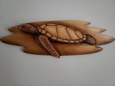 a carved wooden turtle sitting on top of a piece of wood