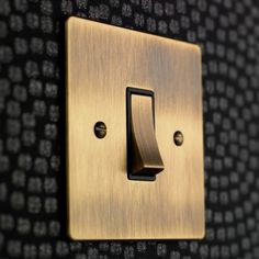 a gold light switch on a black wall with numbers in the backgrounnd