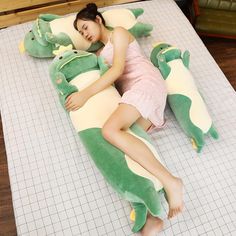 a woman laying on top of a green and yellow alligator pillow