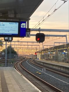 the train tracks are empty and there is a red light at the end of the track