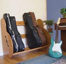 three guitars are lined up on a shelf next to a piano and potted plant