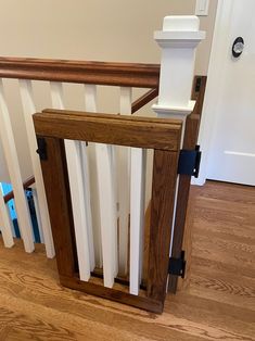 a wooden banister sitting on top of a hard wood floor next to a white door