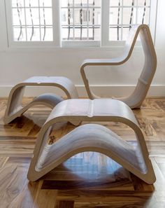 a chair and ottoman sitting on top of a hard wood floor next to a window