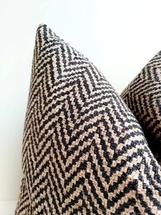 two black and white chevroned pillows sitting on top of each other in front of a white wall