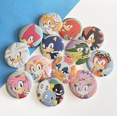 a bunch of sonic the hedgehog buttons sitting on top of a blue and white table