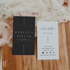 a white and black business card sitting on top of a wooden table next to a fur rug