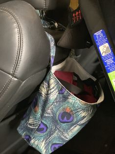 the inside of a car seat with a peacock print bag hanging from it's center console