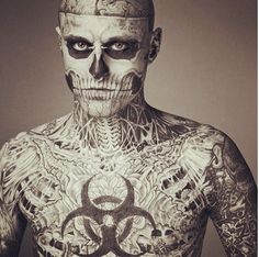 a man with tattoos on his body and face is standing in front of the camera