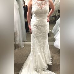 a woman standing in front of a mirror wearing a wedding dress and looking at the camera